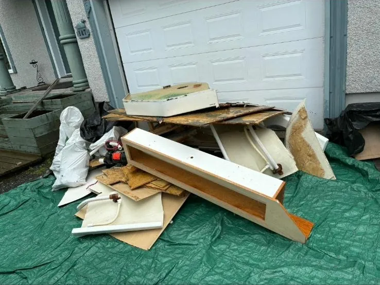 Débris de rénovation sur une bâche devant un garage
